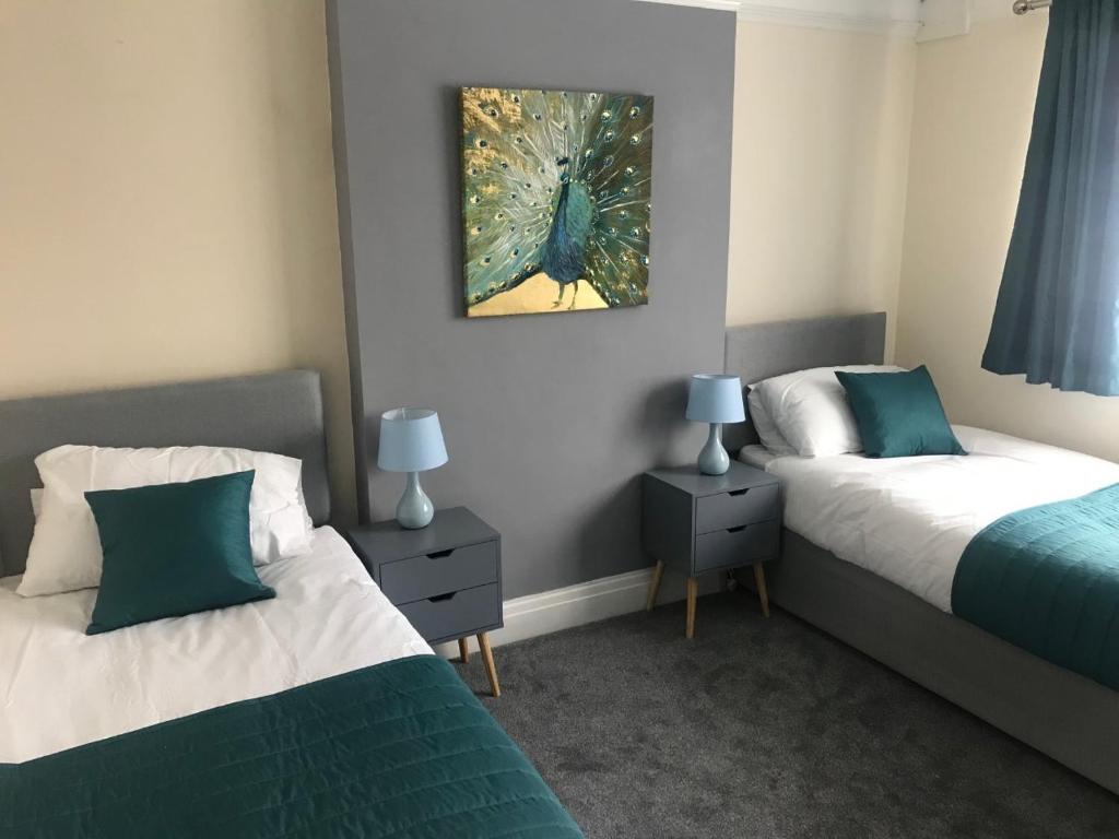 a bedroom with two beds and a painting on the wall at Tudors in Chelmsford