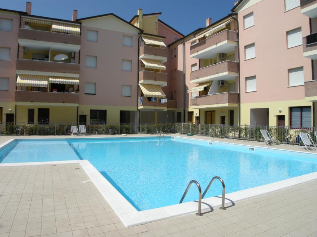 uma piscina em frente a alguns edifícios de apartamentos em Acquasmeralda appartamento 01 em Rosolina Mare