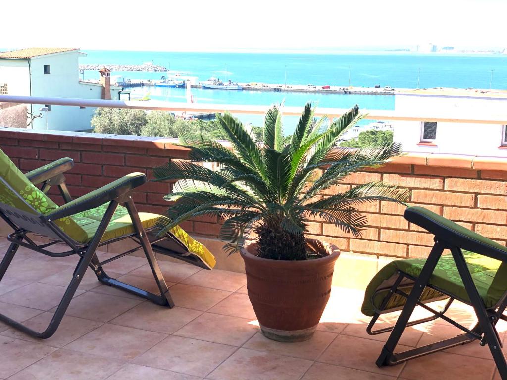 une plante dans un pot sur un balcon avec deux chaises dans l'établissement NAUTICA 10 - Apartamento terraza con vistas al mar - aire acondicionado - cerca puerto, playa y centro, à Roses