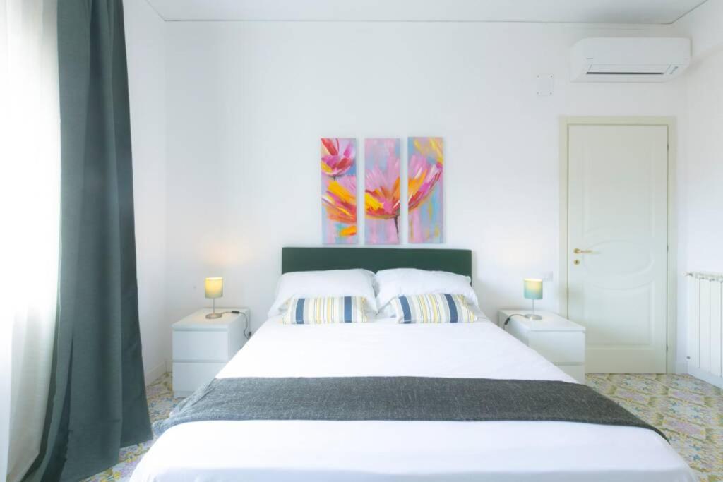 een slaapkamer met een wit bed en een schilderij aan de muur bij Cozy Sorrento Apartment in Sorrento