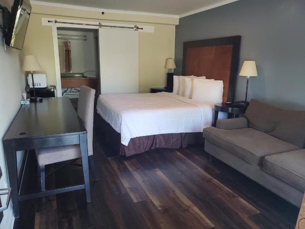 マディソンにあるDeerfield Inn & Suitesのベッド、デスク、ソファが備わるホテルルームです。