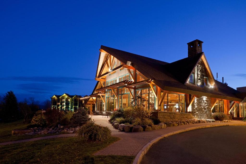een groot houten gebouw met 's nachts verlichting bij Crowne Plaza Lake Placid, an IHG Hotel in Lake Placid