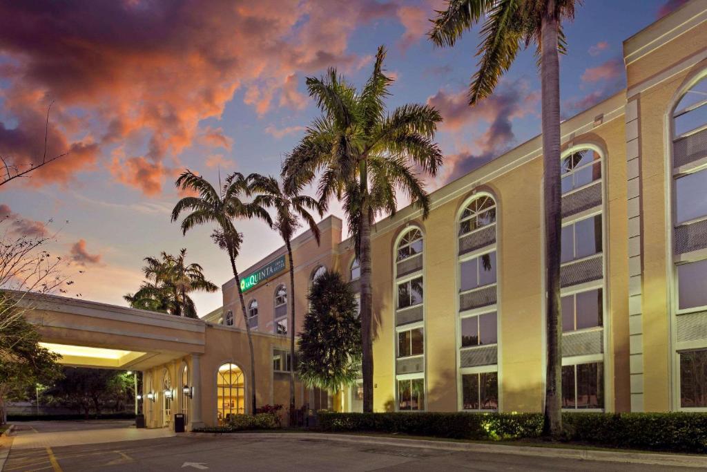a rendering of the exterior of a hotel with palm trees at La Quinta Inn & Suites by Wyndham Sunrise in Sunrise