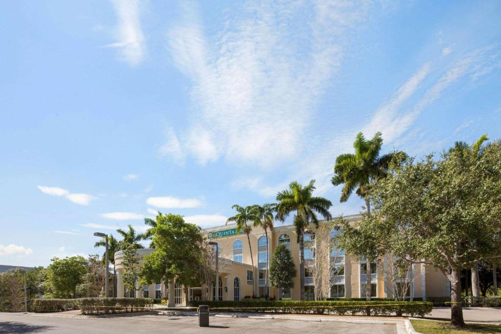 a building with palm trees in front of it at La Quinta Inn & Suites by Wyndham Sunrise in Sunrise