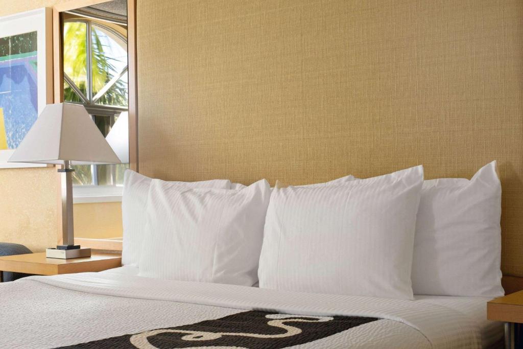 a bedroom with a bed with white pillows and a window at La Quinta Inn & Suites by Wyndham Sunrise in Sunrise