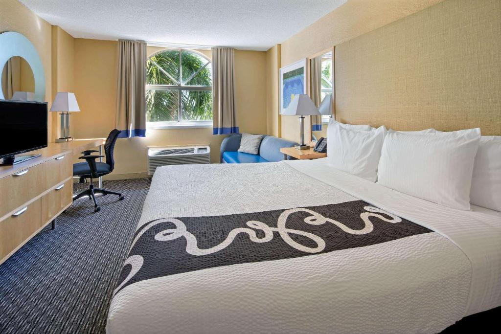 a hotel room with a large bed and a television at La Quinta Inn & Suites by Wyndham Sunrise in Sunrise