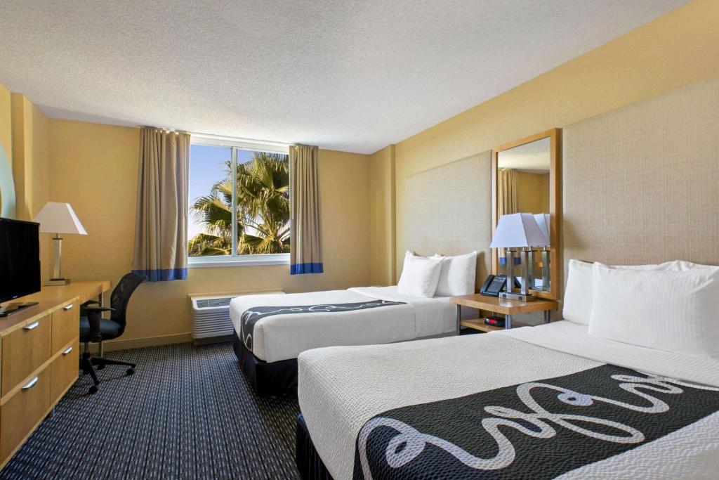 a hotel room with two beds and a television at La Quinta Inn & Suites by Wyndham Sunrise in Sunrise