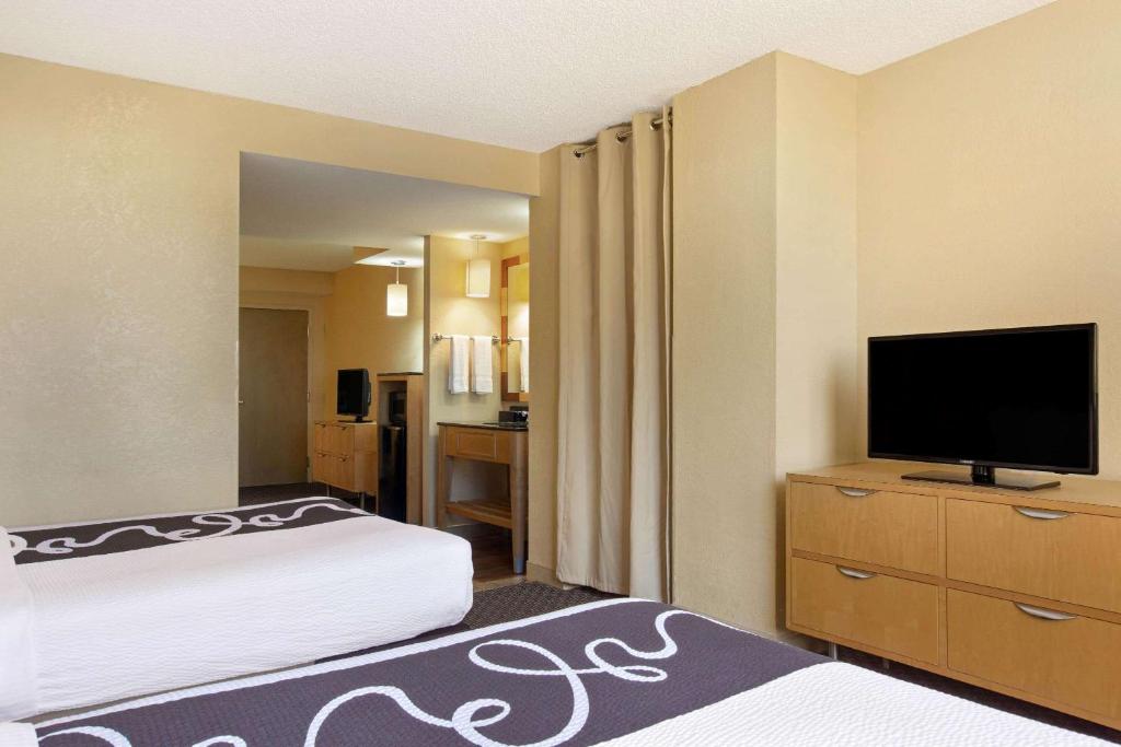 a hotel room with two beds and a flat screen tv at La Quinta Inn & Suites by Wyndham Sunrise in Sunrise
