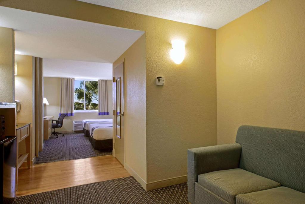 a hotel room with a bed and a living room at La Quinta Inn & Suites by Wyndham Sunrise in Sunrise