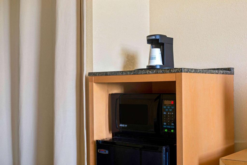 a tv on a stand with a bottle on top of it at La Quinta Inn & Suites by Wyndham Sunrise in Sunrise