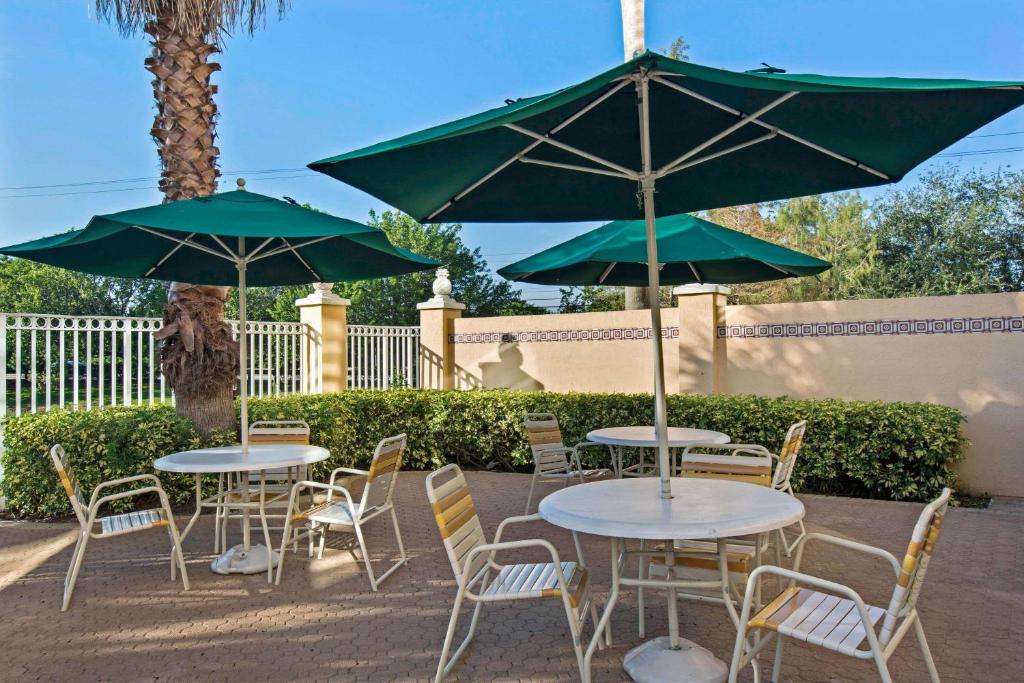 a group of tables and chairs with green umbrellas at La Quinta Inn & Suites by Wyndham Sunrise in Sunrise