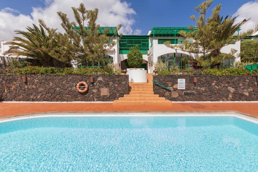 a swimming pool in front of a house with a staircase at Conylanza Golf y Mar Suites in Costa Teguise