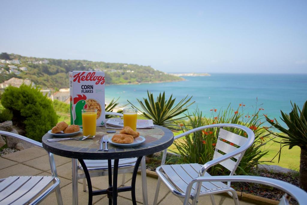 a table with food and drinks on a balcony with the ocean at Beach View in St Ives