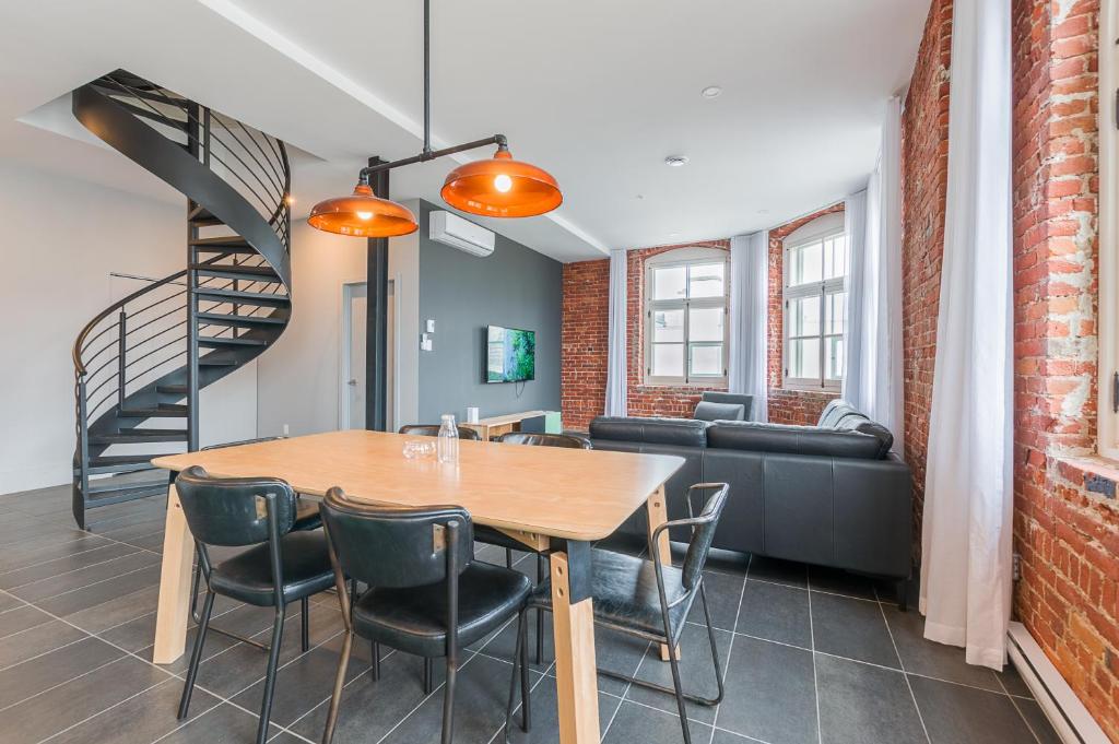 a dining room with a table and chairs and a staircase at Les Lofts du Trésor - Par Les Lofts Vieux-Québec in Quebec City