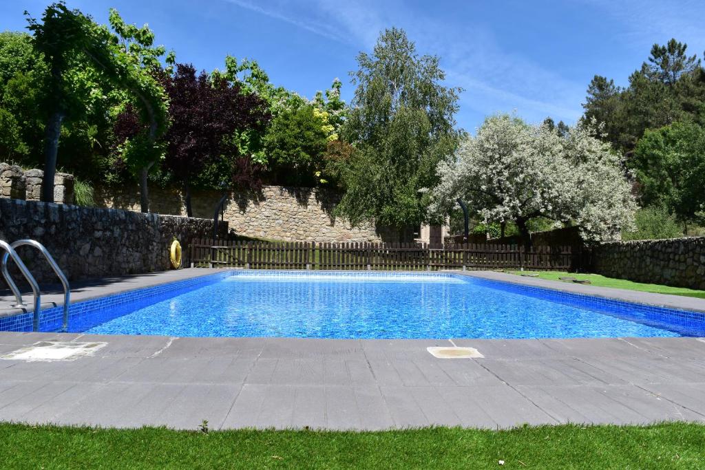 a swimming pool in a yard next to a fence at HOTEL RURAL A VELHA FABRICA in Valverde del Fresno