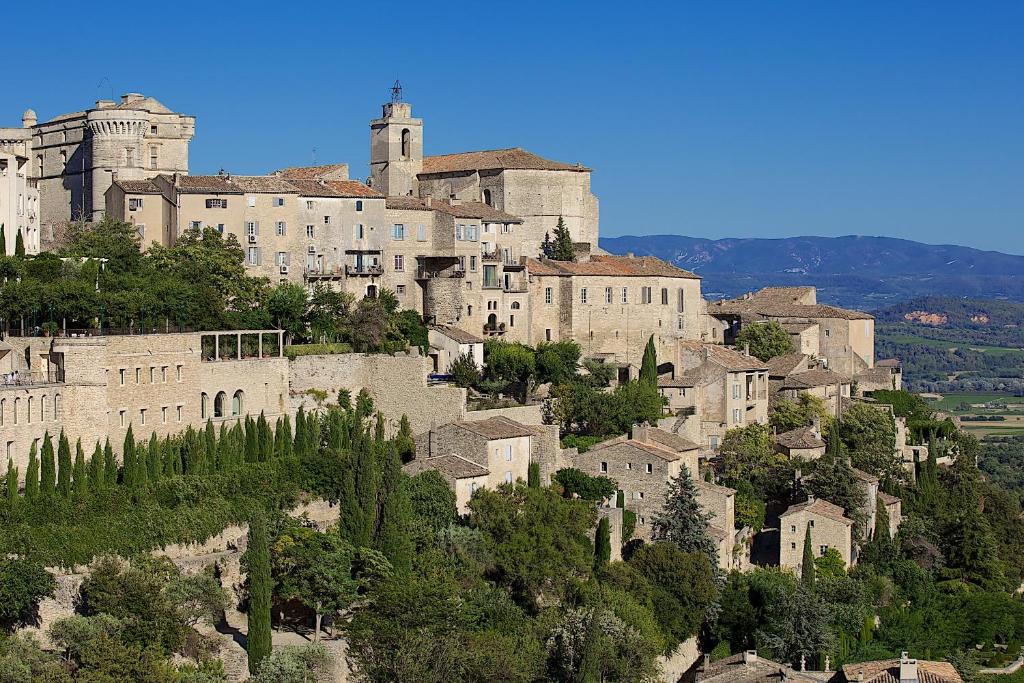 un gran castillo en la cima de una montaña en Apartments - Experience of PROVENCE en Gordes