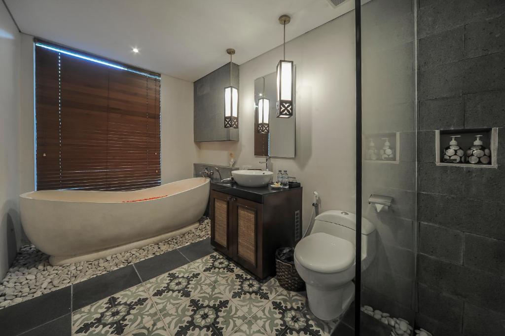 a bathroom with a tub and a toilet and a sink at Gaing Mas Jimbaran Villas by Gaing Mas Group in Jimbaran