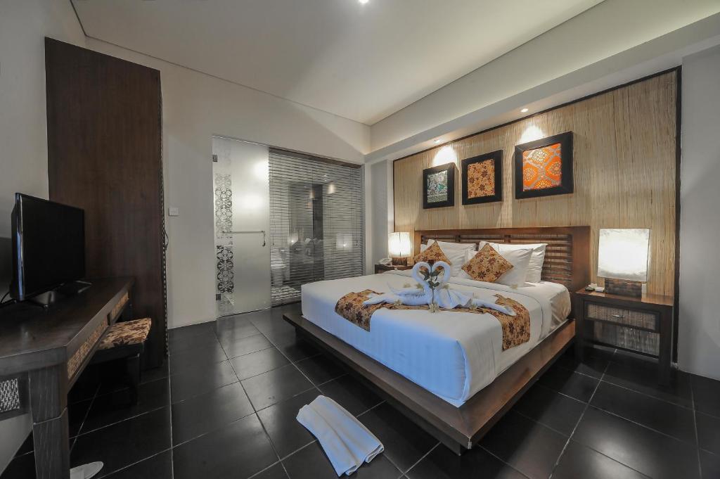 a bedroom with a large bed and a television at Gaing Mas Jimbaran Villas by Gaing Mas Group in Jimbaran
