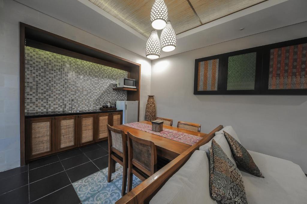 a dining room with a table and a kitchen at Gaing Mas Jimbaran Villas by Gaing Mas Group in Jimbaran