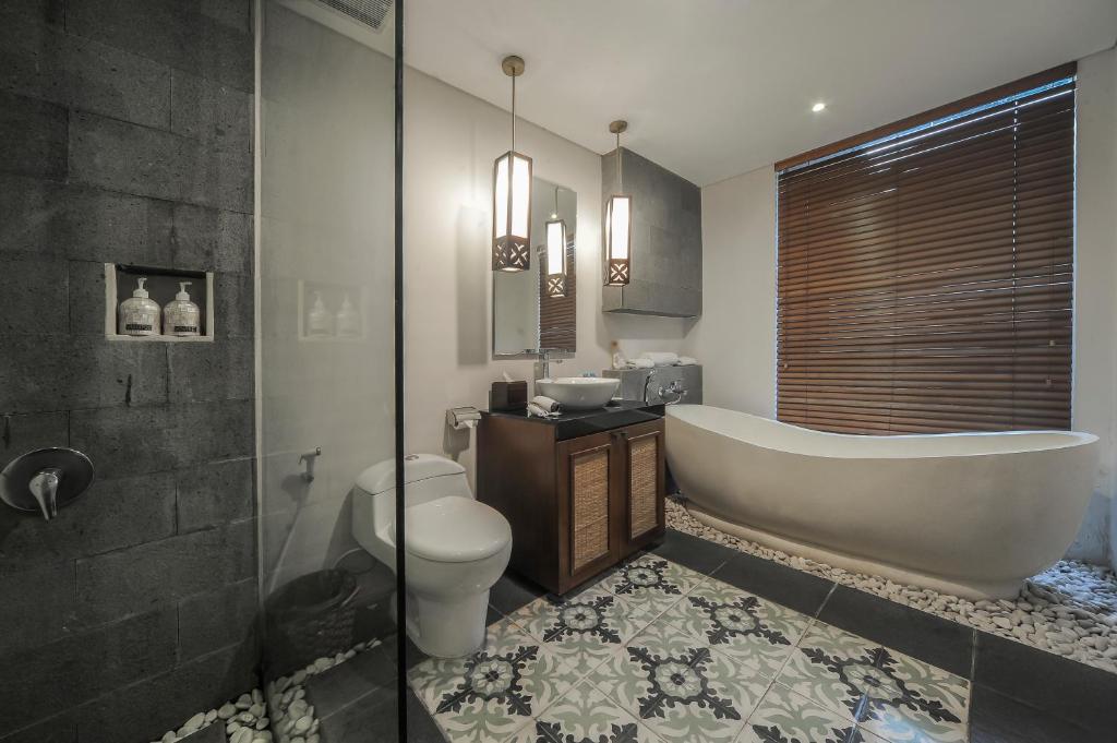 a bathroom with a tub and a toilet and a sink at Gaing Mas Jimbaran Villas by Gaing Mas Group in Jimbaran