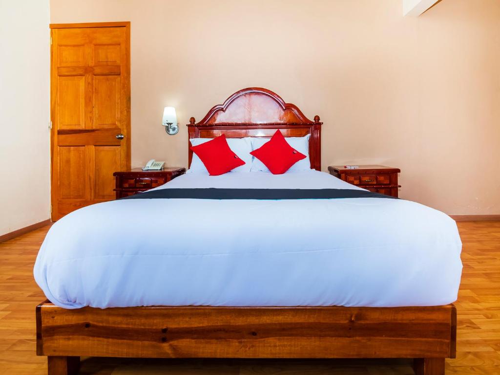 a bedroom with a large white bed with red pillows at Hotel De La Loma in Tlaxcala de Xicohténcatl