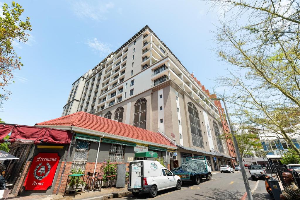 ein großes Gebäude an einer Stadtstraße mit vor der Tür geparkt in der Unterkunft Dockside Apartments in Kapstadt