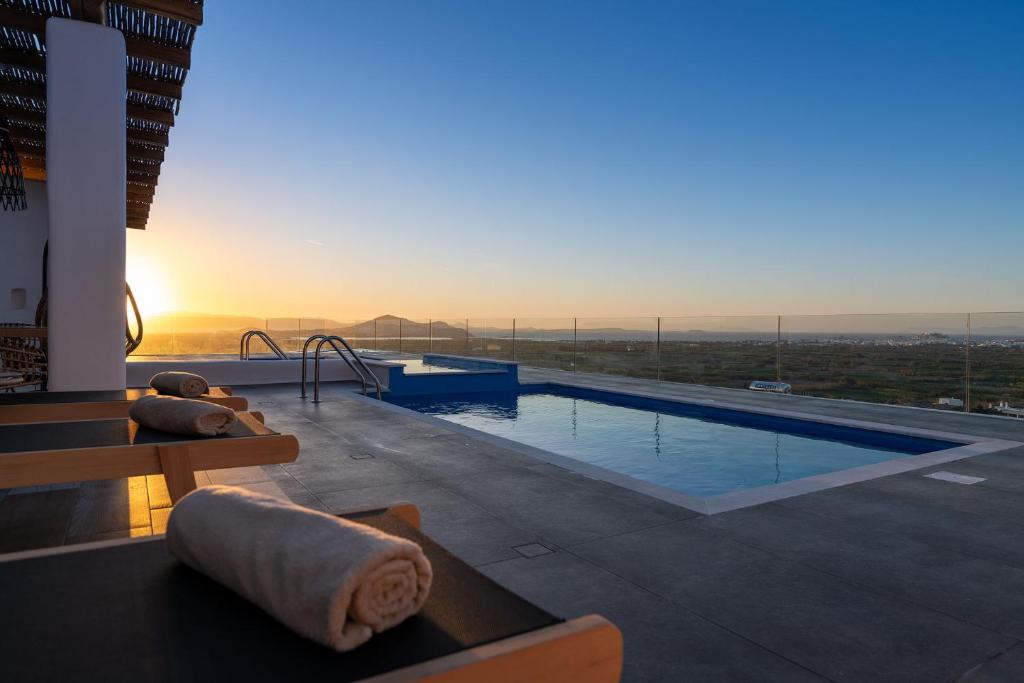 a large swimming pool with a sunset in the background at NAXIAN SUNSET VILLAS in Naxos Chora