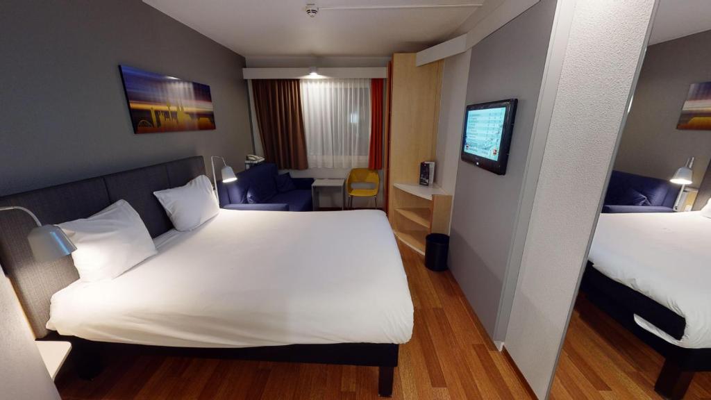 um quarto de hotel com uma cama e uma televisão em ibis Hotel Köln Airport em Colônia