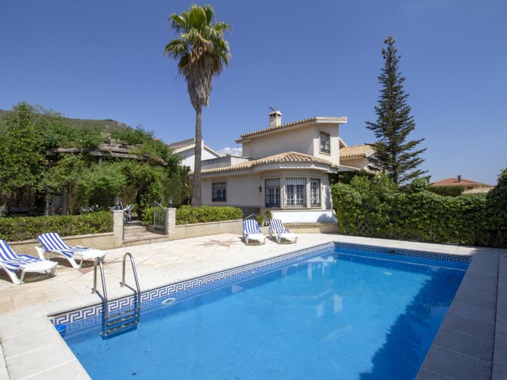 - une piscine en face d'une maison avec un palmier dans l'établissement Villa del mamut, à Padul