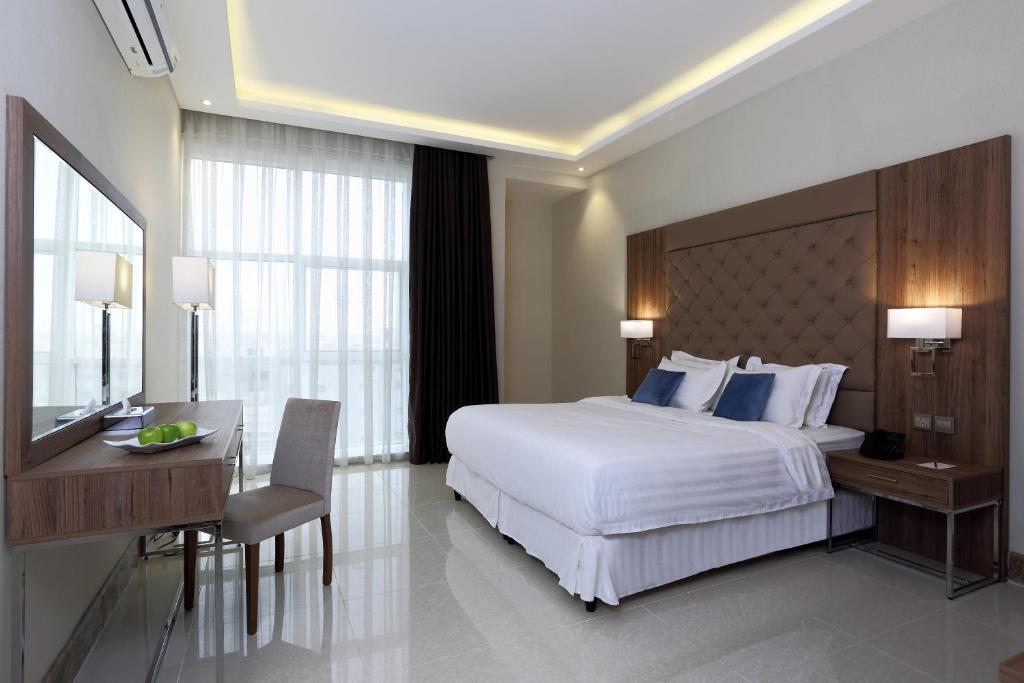 فندق كود العربية Kud Al Arabya Apartment Hotel في خميس مشيط: غرفة نوم مع سرير أبيض كبير ومكتب ومكتب
