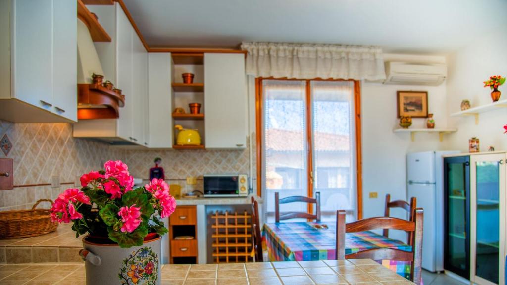 uma cozinha com uma mesa com flores cor-de-rosa em Appartamento Il Marinaio em Porto Azzurro