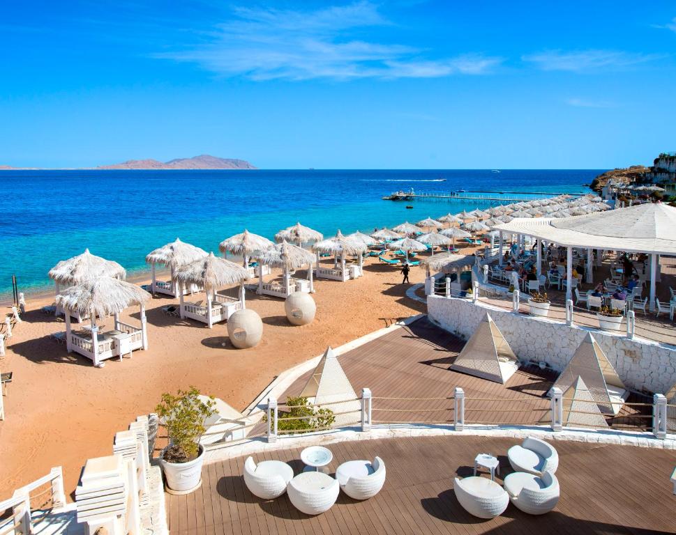 einen Strand mit Liegestühlen und Sonnenschirmen und dem Meer in der Unterkunft Sunrise Arabian Beach Resort in Sharm El Sheikh
