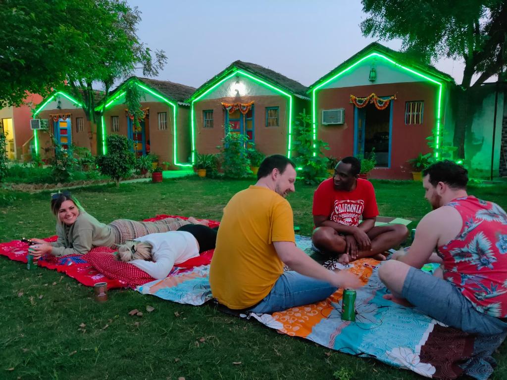 a group of people sitting on a blanket in front of a house at Village Homestay in Agra