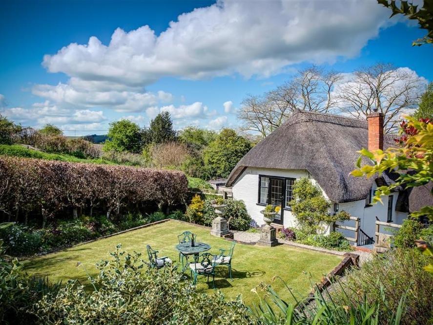 a cottage with a garden with a table and chairs at Foley's Cottage in Warminster