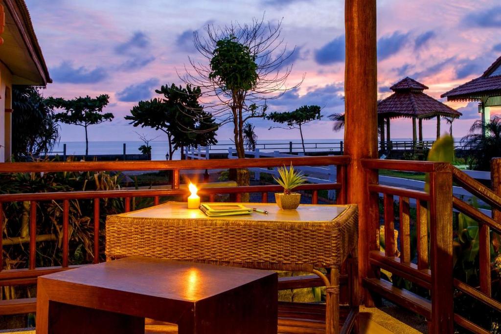 a table and bench on a balcony with a candle at Baan Rabieng Resort in Ko Lanta