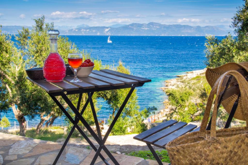 un tavolo con un bicchiere di vino e un cesto di frutta di PaxosBlue Suites & Villas a Gaios