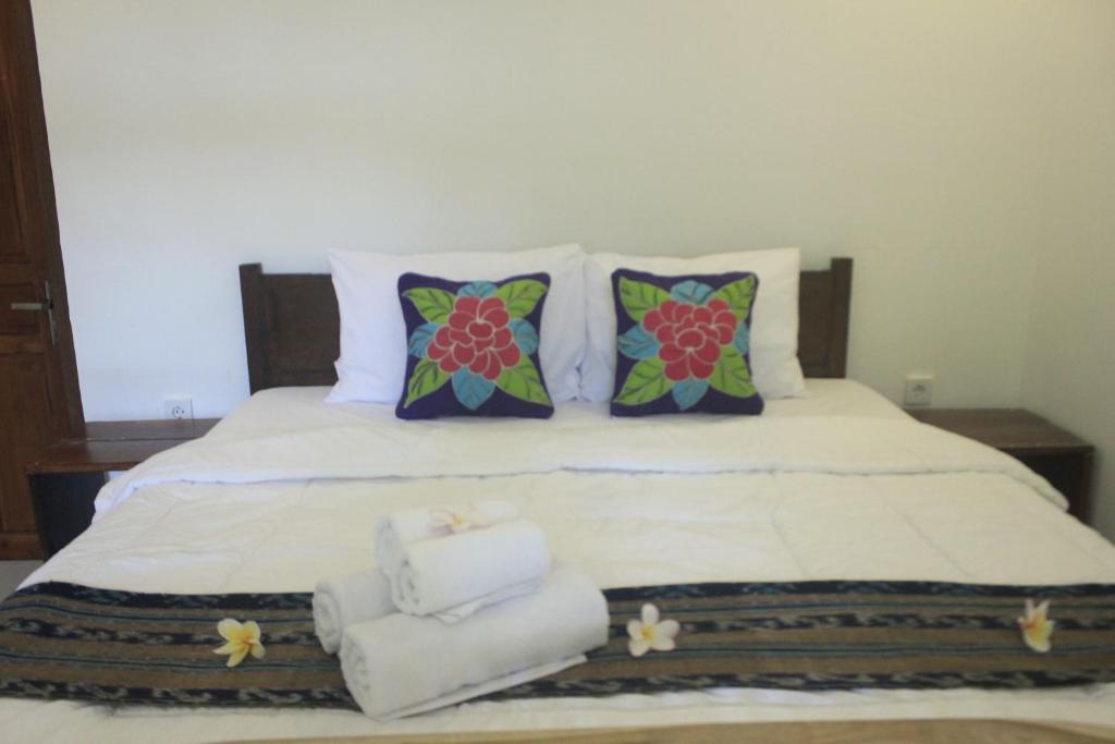 een wit bed met kussens en handdoeken erop bij Umah De Arlika UBUD in Ubud