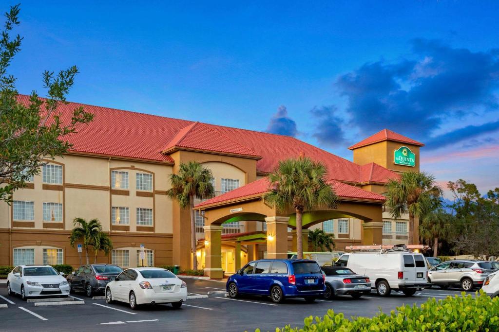 a hotel with cars parked in a parking lot at La Quinta Inn and Suites Fort Myers I-75 in Fort Myers