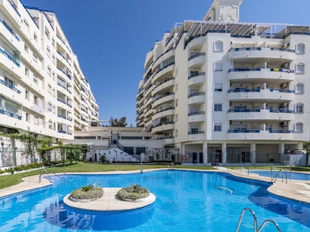 a swimming pool in front of two large buildings at Apartamento 306 in Marbella