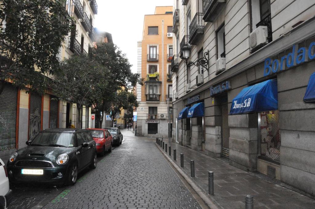 uma rua com carros estacionados na berma da estrada em Hostal Los Arcos em Madrid