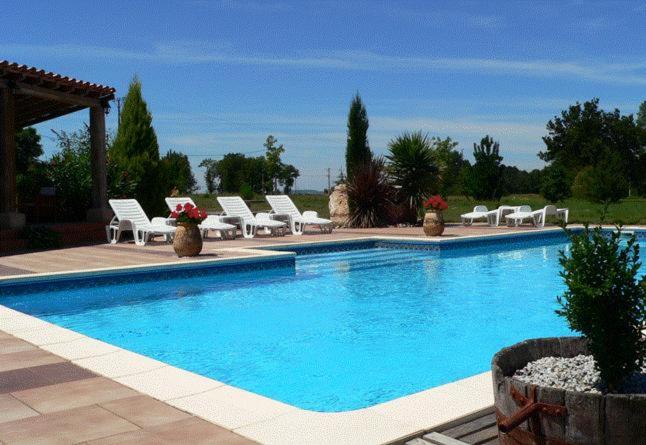 a swimming pool with white chairs and a bunch ofitures at La Terrasse in Sorèze