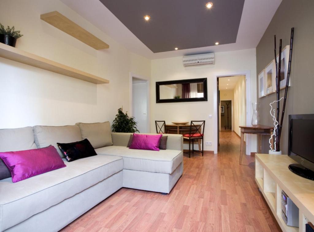 sala de estar con sofá blanco y almohadas rosas en GAUDI Barcelonastuff Apartments, en Barcelona