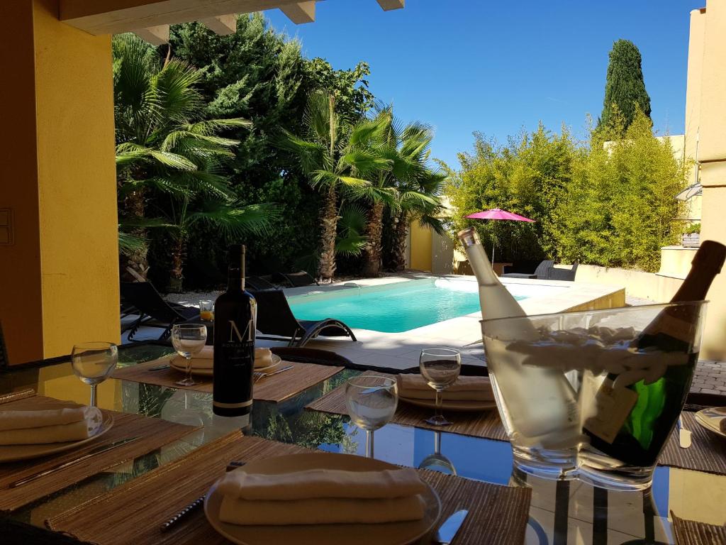 uma mesa com garrafas de vinho e copos ao lado de uma piscina em Villa Bambou Piscine Chauffée em Langlade
