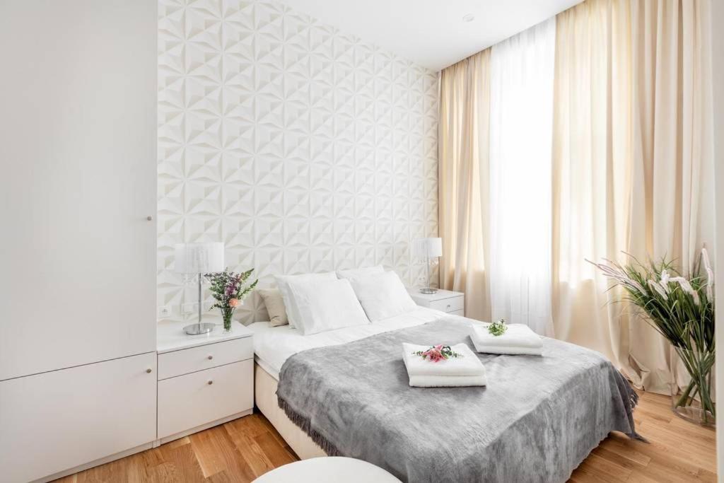 a white bedroom with a bed with two towels on it at Luxury Apartment 60 in Warsaw