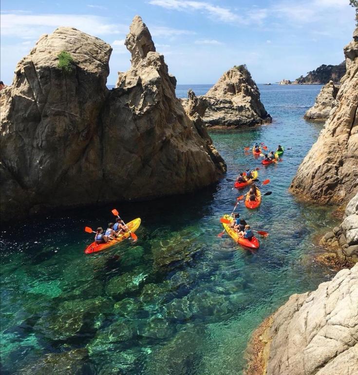 a group of people in kayaks in the water near rocks at SeaHomes Vacations, BEACH&POOL, in Fenals Beach in Lloret de Mar