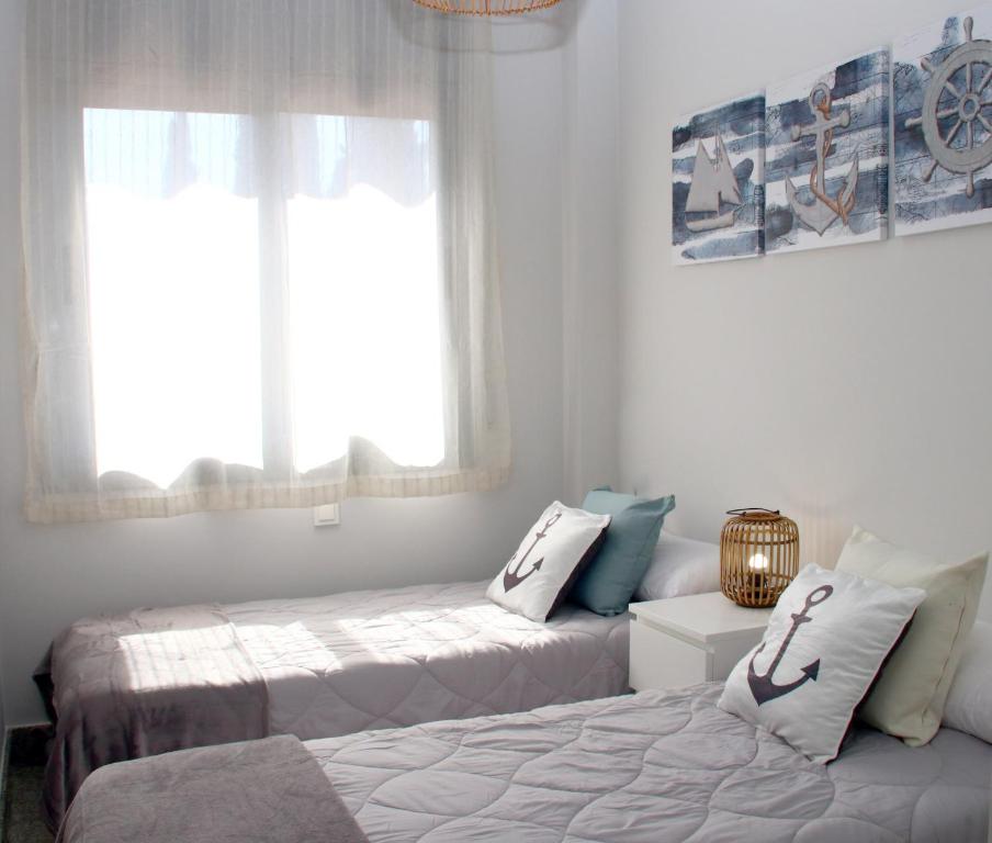 a bedroom with two beds and a window at SeaHomes Vacations, BEACH&POOL, in Fenals Beach in Lloret de Mar