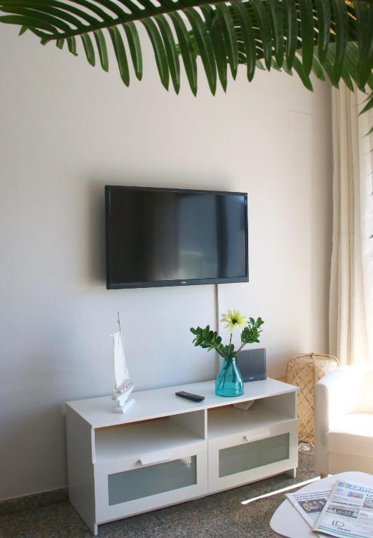 a white entertainment center with a tv on a wall at SeaHomes Vacations, BEACH&POOL, in Fenals Beach in Lloret de Mar