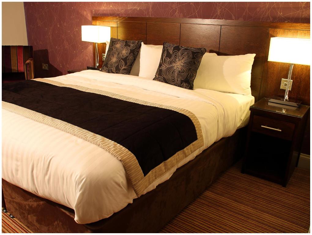 a large bed in a hotel room with two lamps at Blanco's Hotel in Port Talbot