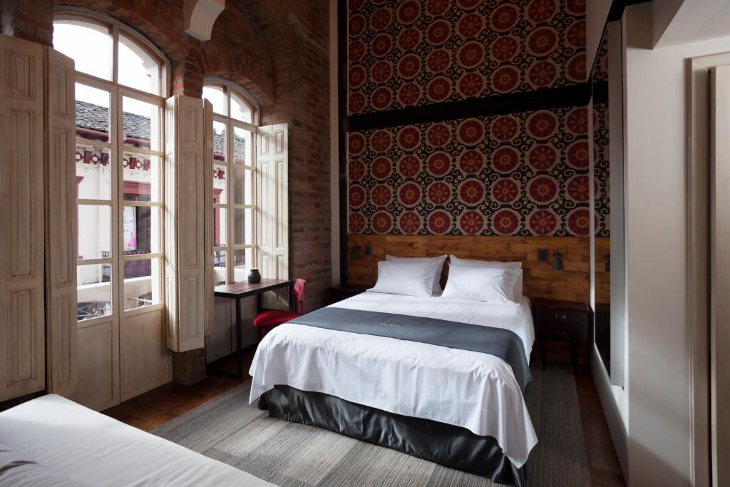 1 dormitorio con 2 camas y pared roja en Carlota Sustainable Design Hotel, en Quito