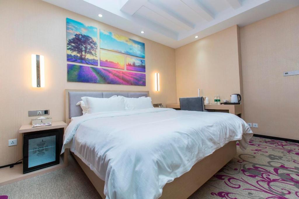 a bedroom with a large bed and a painting on the wall at Lavande Hotels·Dalian Xinghai Park in Dalian